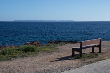 Fototapeta na wymiar Bench for the rest of the walkers in front of the Mediterranean Sea, with the island of Cabrera in the background.