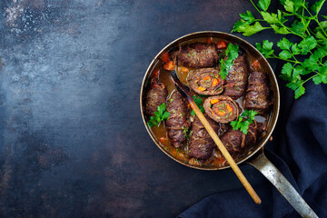 Traditionelle langsam gegarte deutsche Wagyu Rinderrouladen mit Gemüse und Speck serviert in...