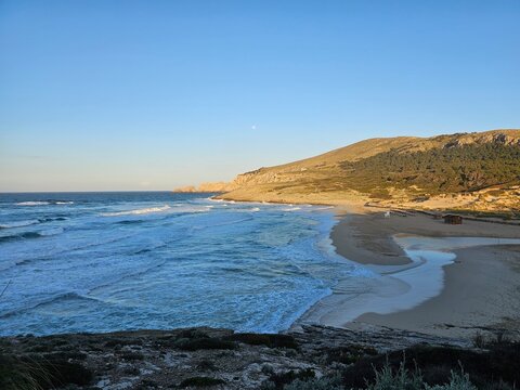 Surf's Up: Waves Rolling in Against a Mountainous Backdrop