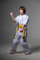 A karate girl trains in a kimono with punches and kicks