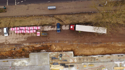 Drone photography of unloading semi truck with a forklift in a construction site during spring cloudy morning.