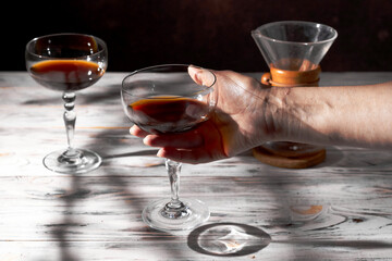 Woman's hand holding a glass of pourover coffee from chemex