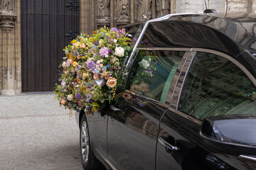 Hearse with floral wreath. Ritual funeral services in a European city.