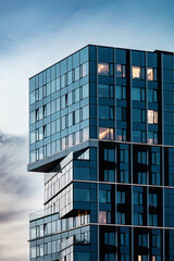 part of a modern glass building against a blue sky with clouds. contemporary cubism design exterior.