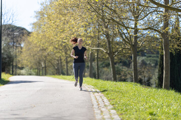 Adult fitness woman jogging on the track in the park