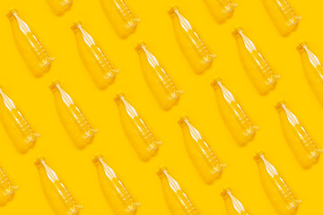 Pattern of transparent plastic bottles on yellow background. Photo collage.