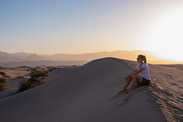 Fototapeta na wymiar Silhouette of woman enjoying the sunrise with scenic view on Mesquite Flat Sand Dunes, Death Valley National Park, California, USA. Morning walk in Mojave desert with Amargosa Mountain Range in back.