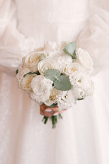 Beautiful wedding white bouquet of roses in the hands of the bride