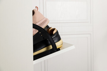 Woman opens Shoe Cabinet with Footwear in hallway. Storage ideas. Seasonal shoes storage