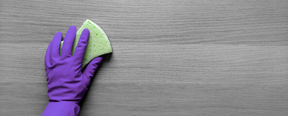 Banner with protective glove and kitchen sponge. Flat lay. Squeaky Clean. Place for text. Gloved hand gives wooden table thorough cleaning with washcloth. Copy space. House cleaning concept. Top view.