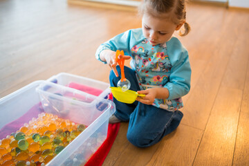 Little girl playing with sensory water beads, hydrogel balls. Sensory development and experiences, themed activities with children, fine motor skills development