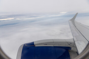view of jet plane wing on the background of thick clouds and blue sky