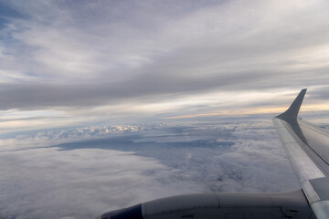 view of jet plane wing on the background of thick clouds and blue sky