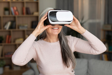 Happy inspired caucasian old lady with vr glasses enjoys leisure time, entertainment with device, wirtual world