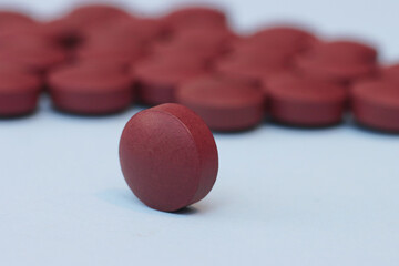 One pill on a blurred background of many pills.