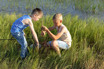 Naklejka na ściany i meble Hobby and leisure activities during summer holidays. Little Caucasian boys brothers at fishing during the summer holidays