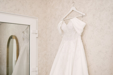 wedding dress on hanger on a wall. Beautiful gown