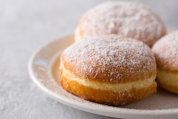 delicious donuts berliners with filling sprinkled with powdered sugar on a white plate