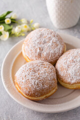 donuts berliners with filling sprinkled with powdered sugar on a white plate