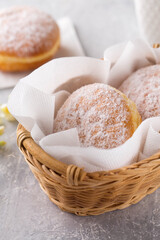 Fototapeta na wymiar delicious donuts berliners with filling sprinkled with powdered sugar in basket on a grey background