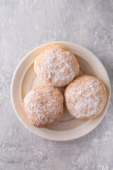 Ruddy delicious donuts berliners with filling sprinkled with powdered sugar on a white plate, top...