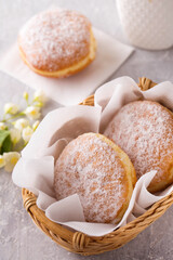Ruddy delicious donuts berliners with filling sprinkled with powdered sugar in basket on a grey background