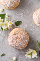 Berliner donuts in powdered sugar with jasmine flowers, top view