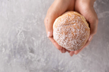 donuts in female hands on a gray background, top view
