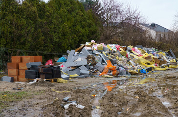 A pile of broken concrete blocks, fiberglass, plastic and other construction debris at a construction site