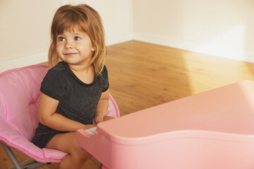 A beautiful child in an evening dress plays the children's piano