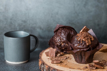 Delicious freshly baked chocolate muffins on a dark background. Delicious cupcake close-up. The context of a bakery with pastries. Confectionery products.