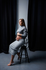 Cute pregnant woman in sweater and skirt with tummy. Happy elegant pregnant woman. A woman is expecting a child