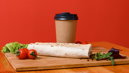 Prepared shawarma on a wooden board with cherry tomatoes and lettuce.