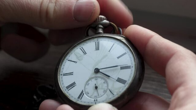 A person twists a dial on a pocket watch