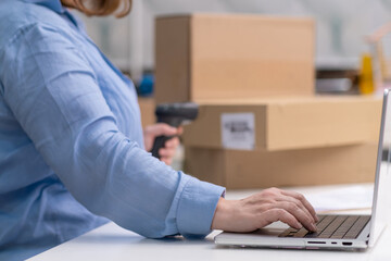 Close up laptop woman checking orders and scanning barcode on cardboard boxes and packages ready for shipping. online marketplace, dropshipping sales and delivery.