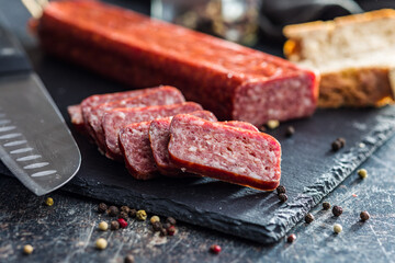 Smoked .sausage. Sliced salami on black table.