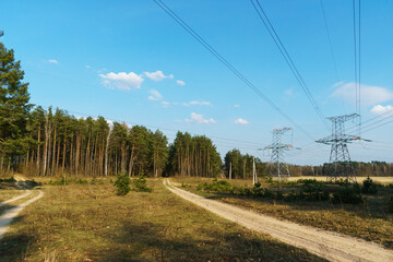 Fototapeta na wymiar An old dirt road in the forest. A high-voltage power line runs through a clearing in a dense forest. Natural forest background.