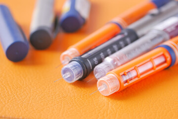 many Insulin pens on orange color background 