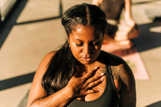 Plus size woman with hand on chest practicing breathing exercise at retreat center - Powered by Adobe