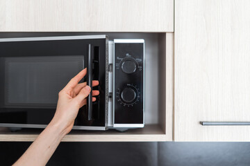 closeup of woman open microwave indoors