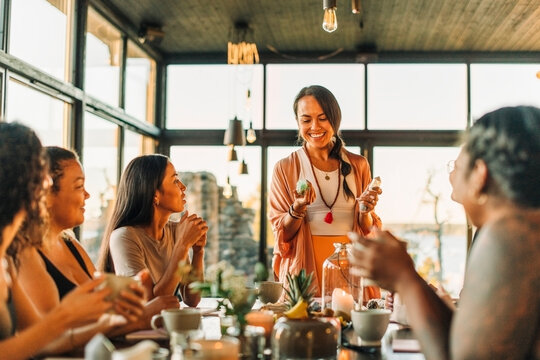 Happy woman holding crystals while discussing with female friends at retreat center