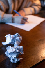 Crumpled paper with a woman hand writing and studying on a wood table background