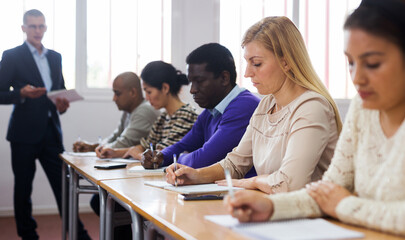 Fototapeta premium Portrait of focused female sitting at desk studying in classroom with colleagues