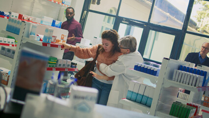 Woman losing consciousness and almost fainting near pharmacy shelves, pharmacist helping dizzy...