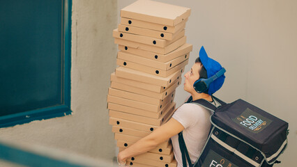 Clumsy food courier trying to catch falling pizza boxes, acting scared and running from client front door after dropping fastfood delivery meal. Afraid carrier with bad service. Handheld shot.