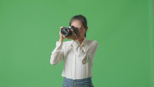 Tried Asian Photographer After Using A Camera Taking Some Pictures While Standing On Green Screen Background In The Studio
