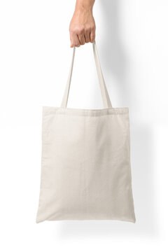 Female hand holding a blank tote canvas bag mockup isolated on a transparent background, PNG. High resolution.