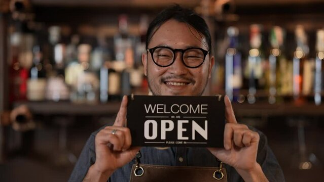 Night club concept of 4k Resolution. Asian man holding a sign welcoming customers in a shop. A group of specialized clubs that sell alcoholic beverages.