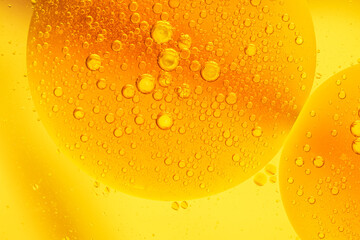 Beautiful cosmetic background. Golden yellow orange abstract oil bubbles or face serum background. Oil and water bubbles macro photography.