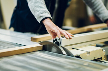 Close up of a craftsman cutting material on a saw.